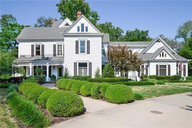 The curved walkway to the front porch is trimmed with brick ribbon and is lined by manicured bushes
