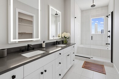 Bathroom featuring light tile patterned floors, double vanity, a walk in closet, and a stall shower