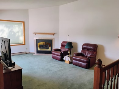 Living room featuring carpet, a tile fireplace, and baseboard heating
