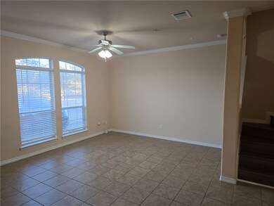 Tiled living room with ceiling fan and crown moldi