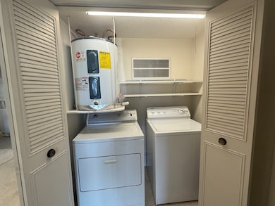 Laundry area with electric water heater, washer and dryer, and a textured ceiling