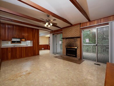 Unfurnished living room featuring wood walls, a sink, a ceiling fan, a fireplace, and light floors