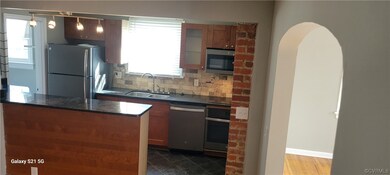 Kitchen featuring sink, appliances with stainless steel finishes, dark tile flooring, decorative light fixtures, and backsplash, newer appliances, bartop area.