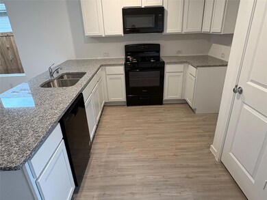 Kitchen with light stone countertops, sink, black 