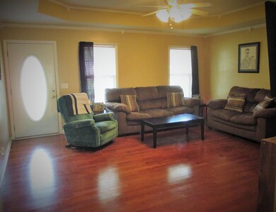 Your living room has plenty of natural light, hardwood flooring, trey ceiling, crown molding, gas log fireplace & ceiling fan lighting.