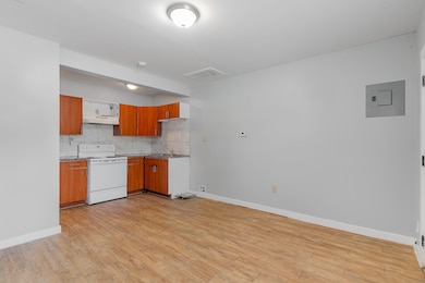 Kitchen featuring tasteful backsplash, electric range, brown cabinetry, and light wood-style floors