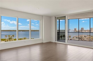 Spacious living/dining area featuring large windows, warm flooring, and serene water views.