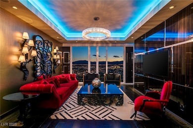 Living room featuring a raised ceiling, wood finished floors, and a chandelier