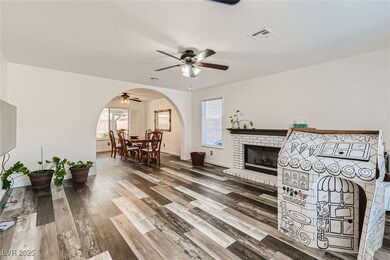 Living room with ceiling fan, a fireplace, arched