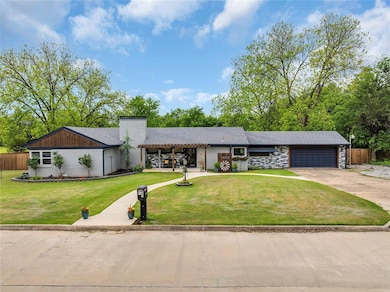 Mid-century modern home featuring driveway, an attached garage, and a chimney