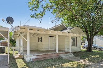 View of front of property with covered porch, roof with shingles, and a front yard