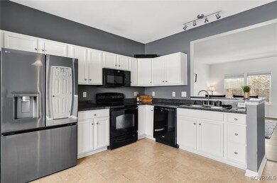 Kitchen with dark stone counters, black appliances
