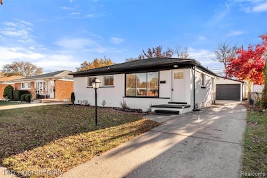 View of front facade featuring an outdoor structure, a garage, brick siding, a front yard, and driveway