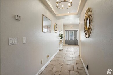 Corridor with a raised ceiling and a chandelier