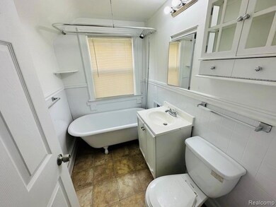 Bathroom featuring vanity, a freestanding tub, wainscoting, and tile walls