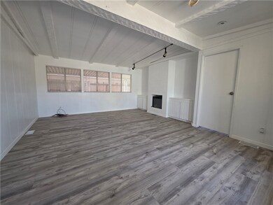 Unfurnished living room featuring beam ceiling, a fireplace, and wood finished floors