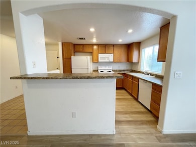Kitchen featuring white appliances, a sink, recess