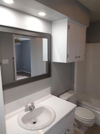Bathroom with vanity, a ceiling fan, a textured w