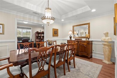 Dining room with ornamental molding, wood finished floors, wainscoting, a chandelier, and recessed lighting