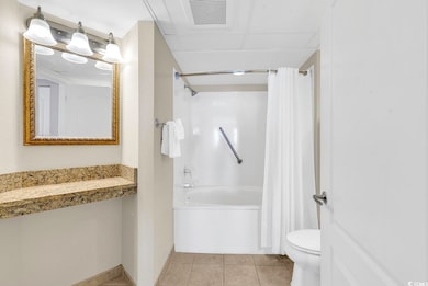 Full bath with shower / bath combination with curtain, toilet, and tile patterned flooring