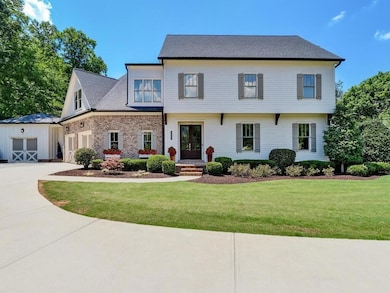 View of front of property featuring concrete driveway, a garage, a front lawn, french doors, and brick siding