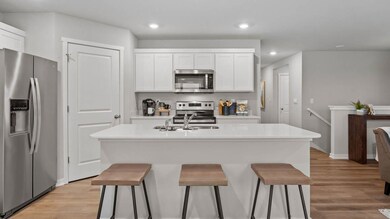 Modern kitchen with stainless steel appliances and microwave venting outside. Model home, finishes will vary.