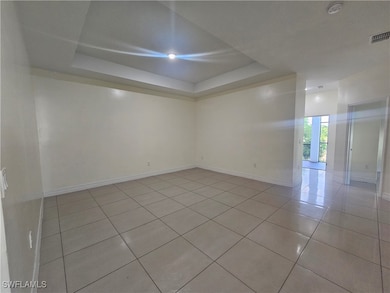 Spare room with a tray ceiling, light tile pattern