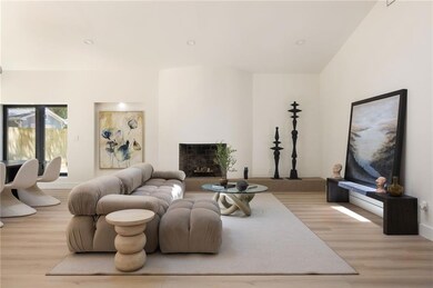 Living room featuring a skylight, a fireplace, wood finished floors, vaulted ceiling, and recessed lighting