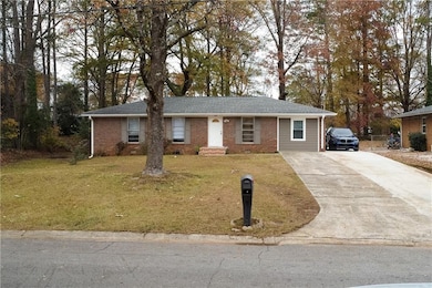 Single story home featuring driveway, a front yard, and brick siding