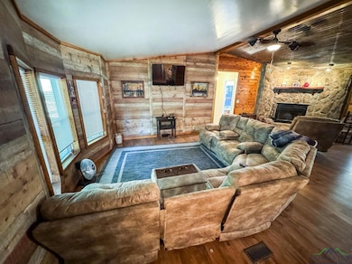 Living area with wood finished floors, wooden walls, lofted ceiling, and a fireplace