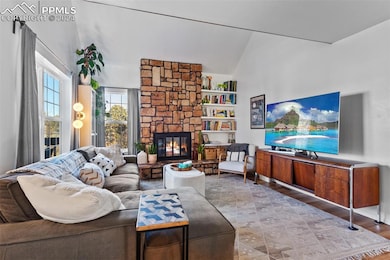 Living room featuring a fireplace, and vaulted cei