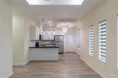 Kitchen featuring white cabinets, tasteful backsplash, pendant lighting, stainless steel appliances, and light wood-type flooring