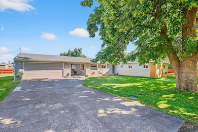 Ranch-style house with driveway, an attached garage, a front yard, and roof with shingles
