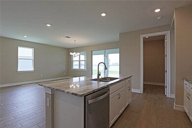 Kitchen with dishwasher, white cabinets, wood finished floors, light stone counters, and a chandelier