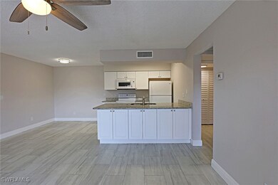 Kitchen featuring white appliances, a sink, basebo