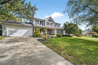 Traditional home featuring a front lawn, covered porch, driveway, and an attached garage