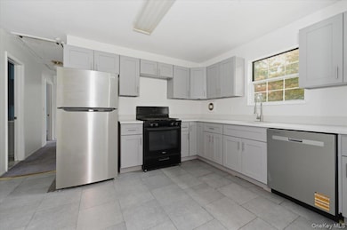 Kitchen with appliances with stainless steel finishes, gray cabinetry, and light tile patterned flooring