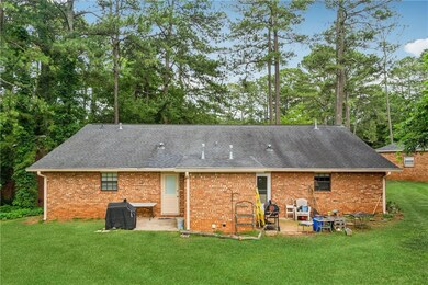 Rear view of property with a patio, a yard, roof with shingles, and brick siding