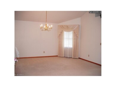Vaulted formal dining room with neutral carpet and window treatments
