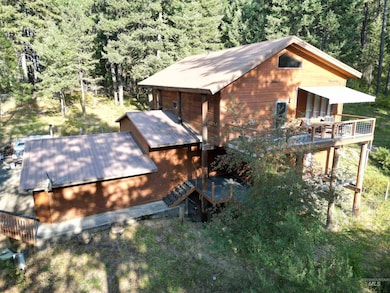 View of property exterior with a forest view, a metal roof, stairs, and a wooden deck