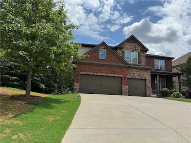 View of front facade with driveway, a front yard, an attached garage, brick siding, and stone siding