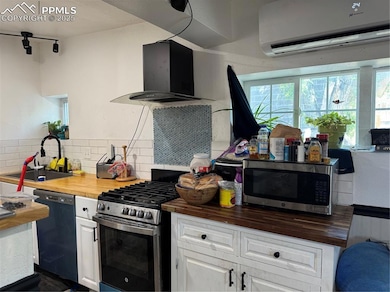 Kitchen with wood counters, stove, dishwashing machine, extractor fan, and an AC wall unit