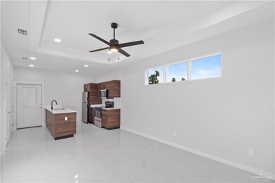 Bedroom with stainless steel refrigerator, ceiling fan, a raised ceiling, and sink
