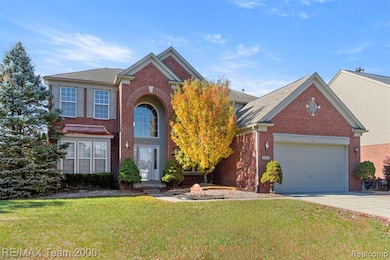 View of front of property with a front yard, concrete driveway, brick siding, roof with shingles, and an attached garage