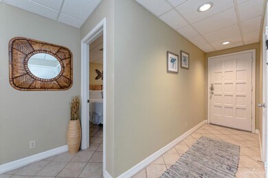 Corridor featuring light tile patterned flooring, baseboards, and a drop ceiling