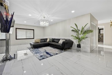 Living area featuring a chandelier, recessed lighting, and marble finish floors