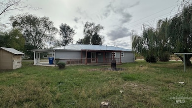 Rear view of house featuring a lawn, a metal roof, an attached carport, a storage shed, and a deck