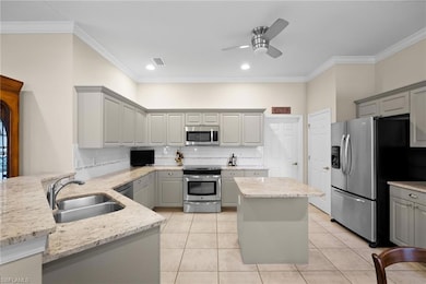 Kitchen featuring gray cabinets, ornamental molding, light tile patterned floors, stainless steel appliances, and decorative backsplash
