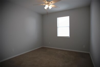 Carpeted empty room featuring ceiling fan and bas