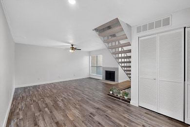 Unfurnished living room with a fireplace with flush hearth, wood finished floors, and a ceiling fan